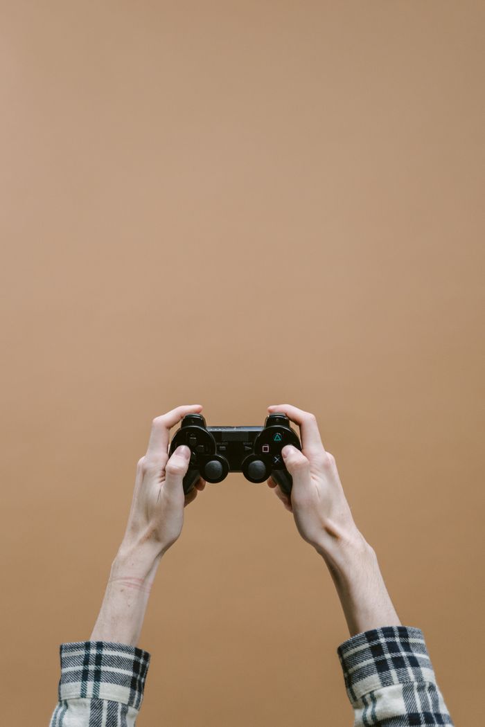 The Art of Drawing Readers In: Your attractive post title goes here A person holds a video game controller with both hands in front of a solid brown backdrop.